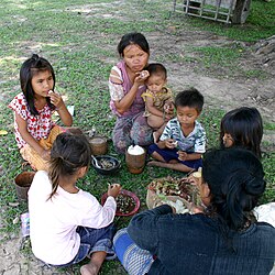 2名東南亞女性和5名兒童坐在草地上吃飯