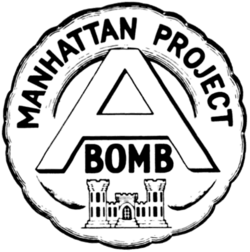 圆形的徽章,顶上书有“Manhattan Project”字样,中间是字母“A”,A下面是“BOMB”。徽章最底部是美国陆军工程兵团的城堡徽章。